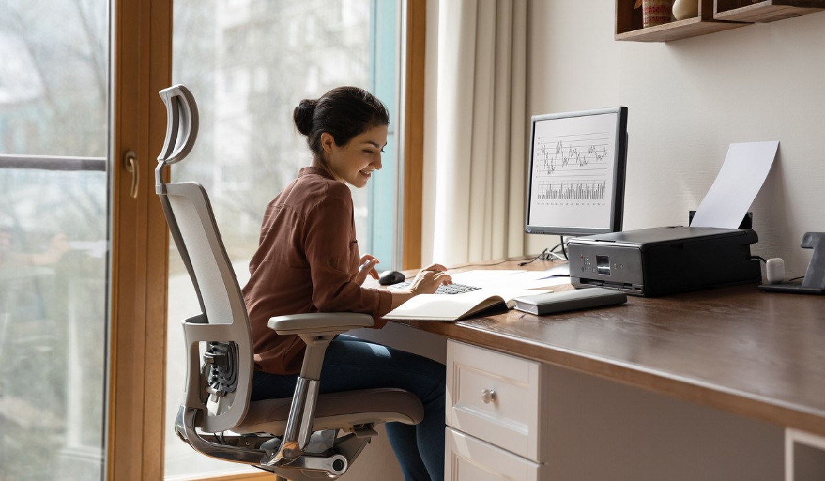 Concentrated young indian ethnicity woman sitting in comfortable adjustable ergonomic armchair