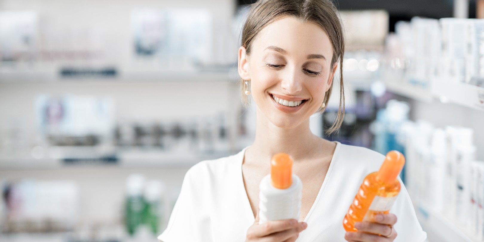 Young woman customer choosing sunscreen lotion at the pharmacy store