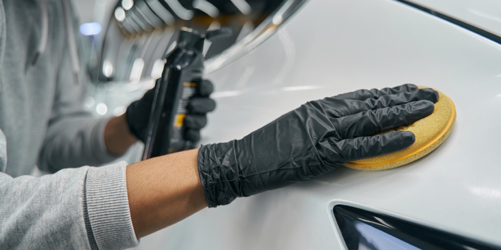 Cropped photo of experienced worker in protective gloves waxing exterior auto body panel