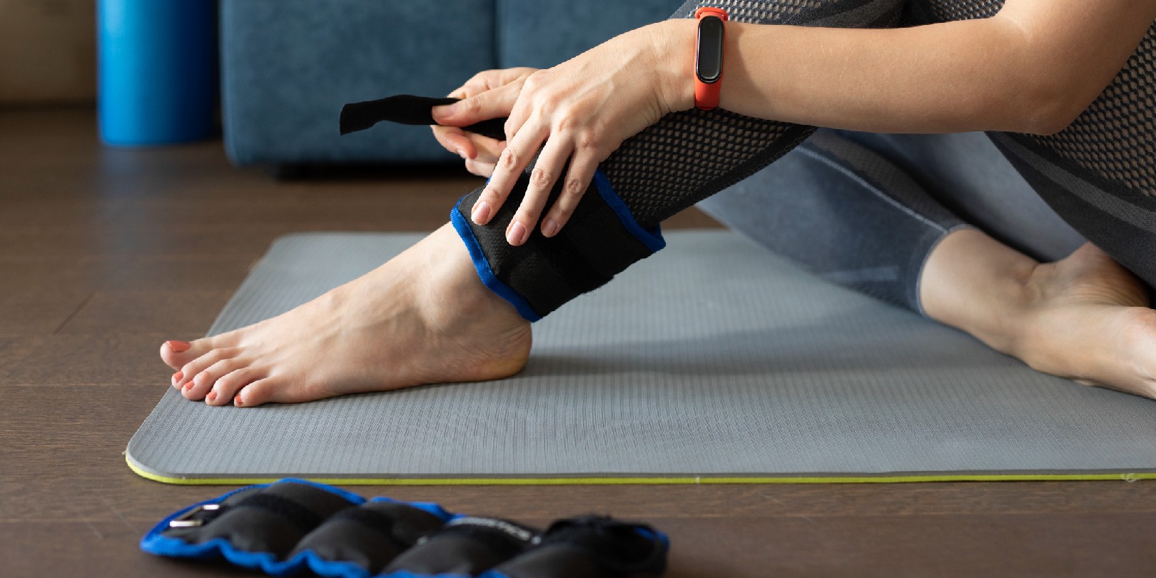 Anonymous woman putting ankle weights on her legs to work out at home.