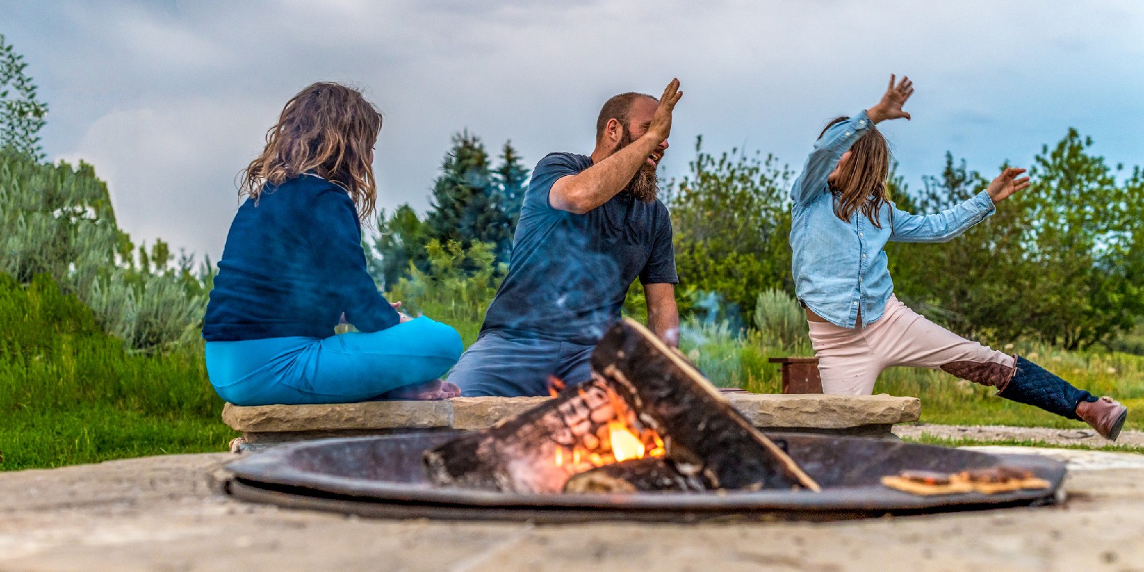 Father on a camping trip with his daughters playing cards around a campfire