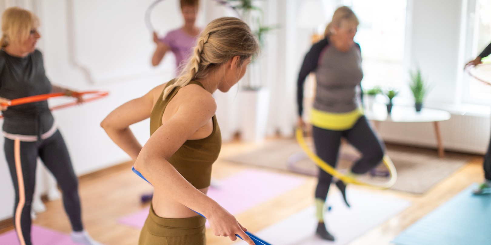 Aerobic instructor and senior people practicing with hula hoop during aerobic class