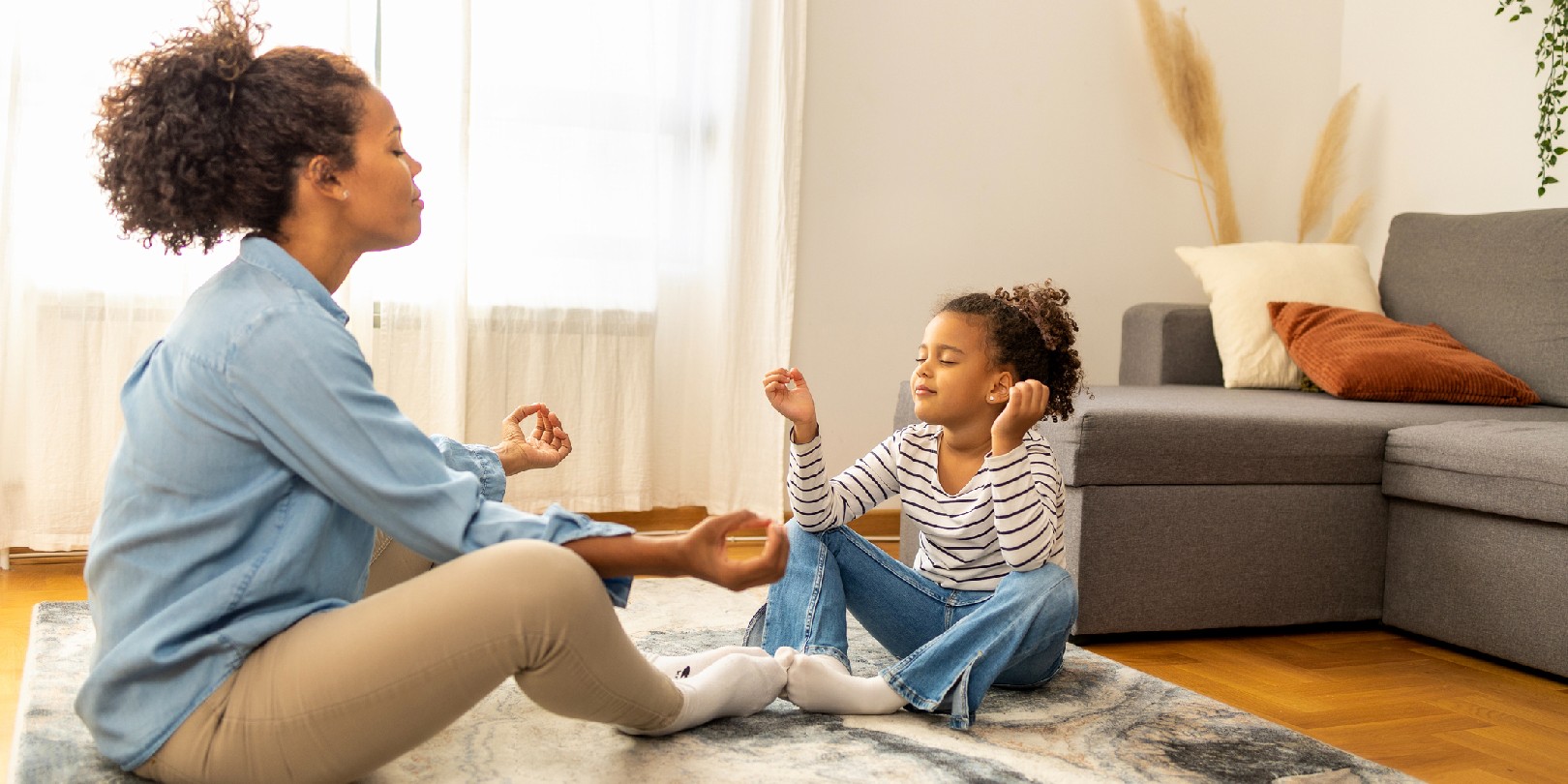 Mother and daughter practice meditation in the living room