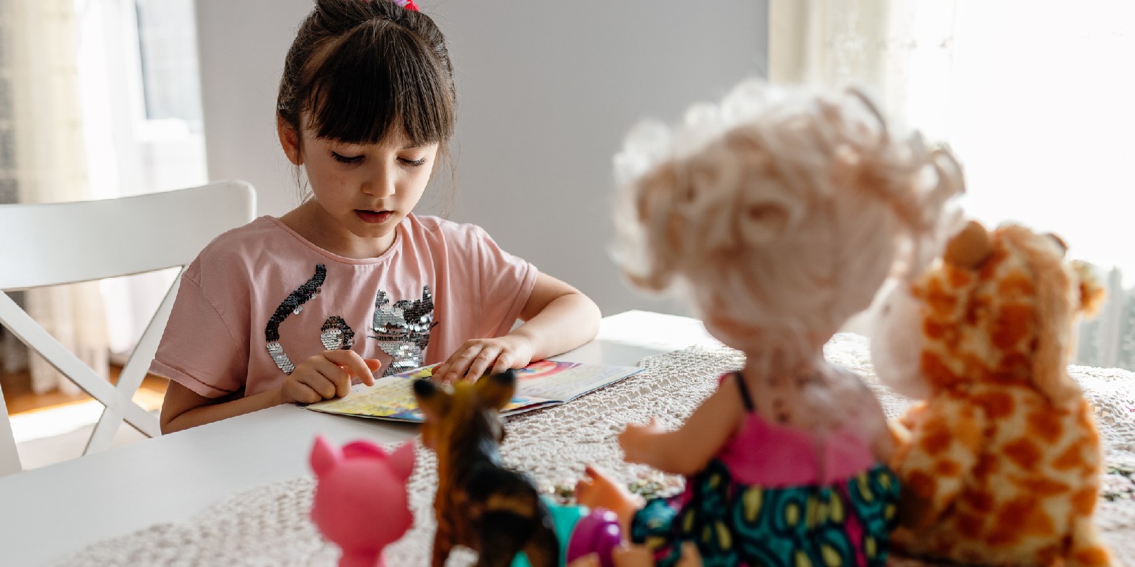 Cute little kid girl playing alone reading book to toys