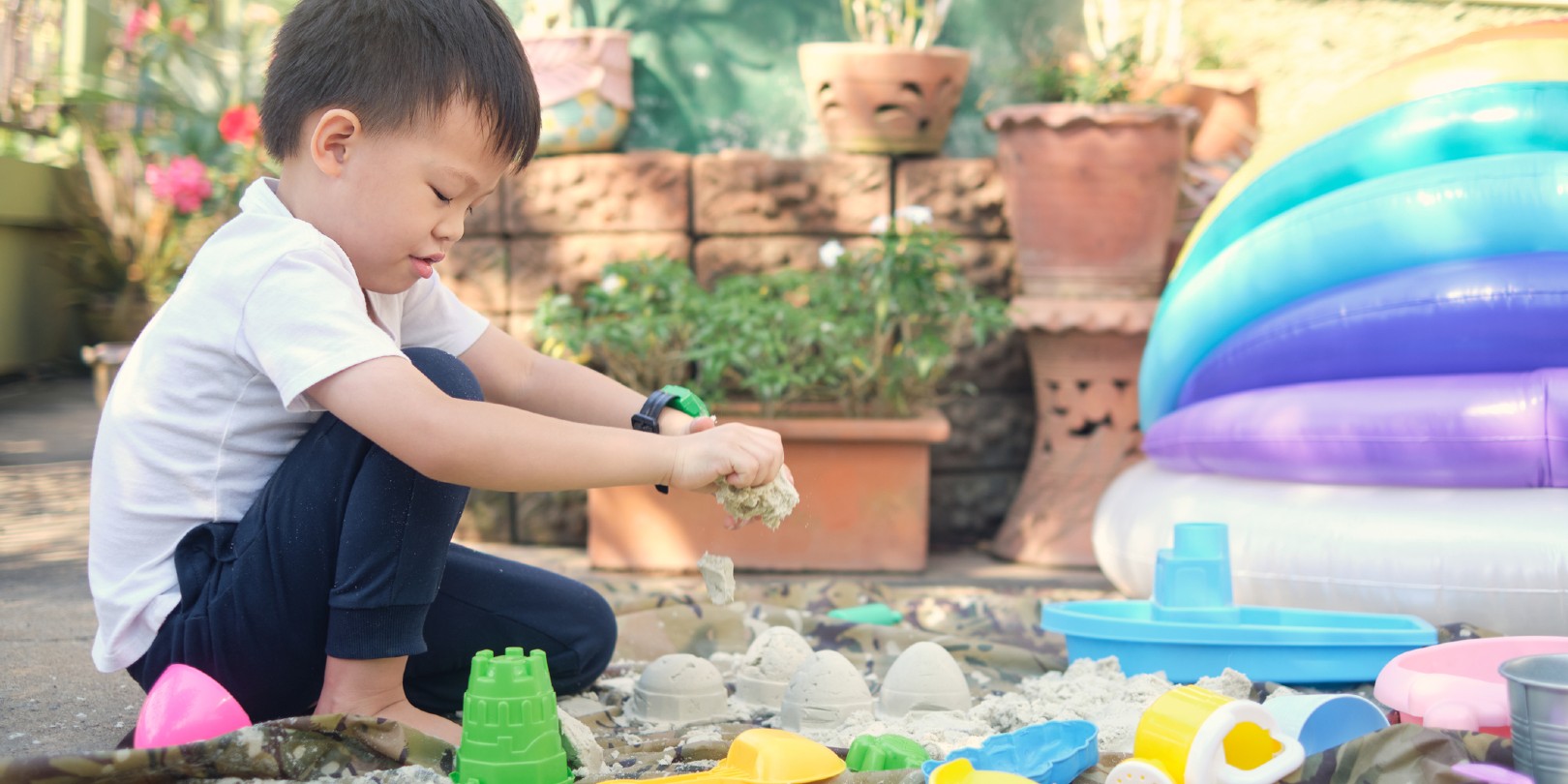 Cute Asian 4 - 5 years old toddler boy playing with sand alone at home