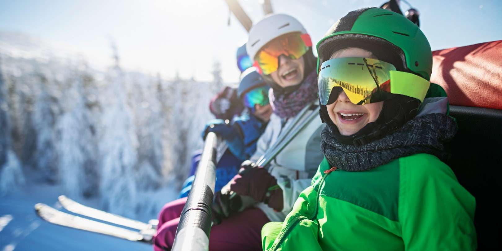 Mother skiing with kids on a sunny winter day. Family is sitting on chairlift cheering at the camera