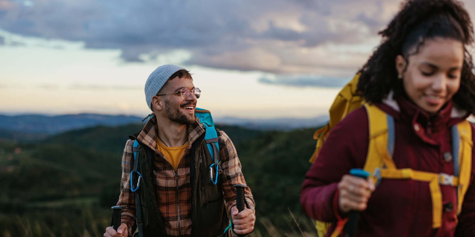 A young cheerful mixed race couple is hiking over the weekend in the mountains.