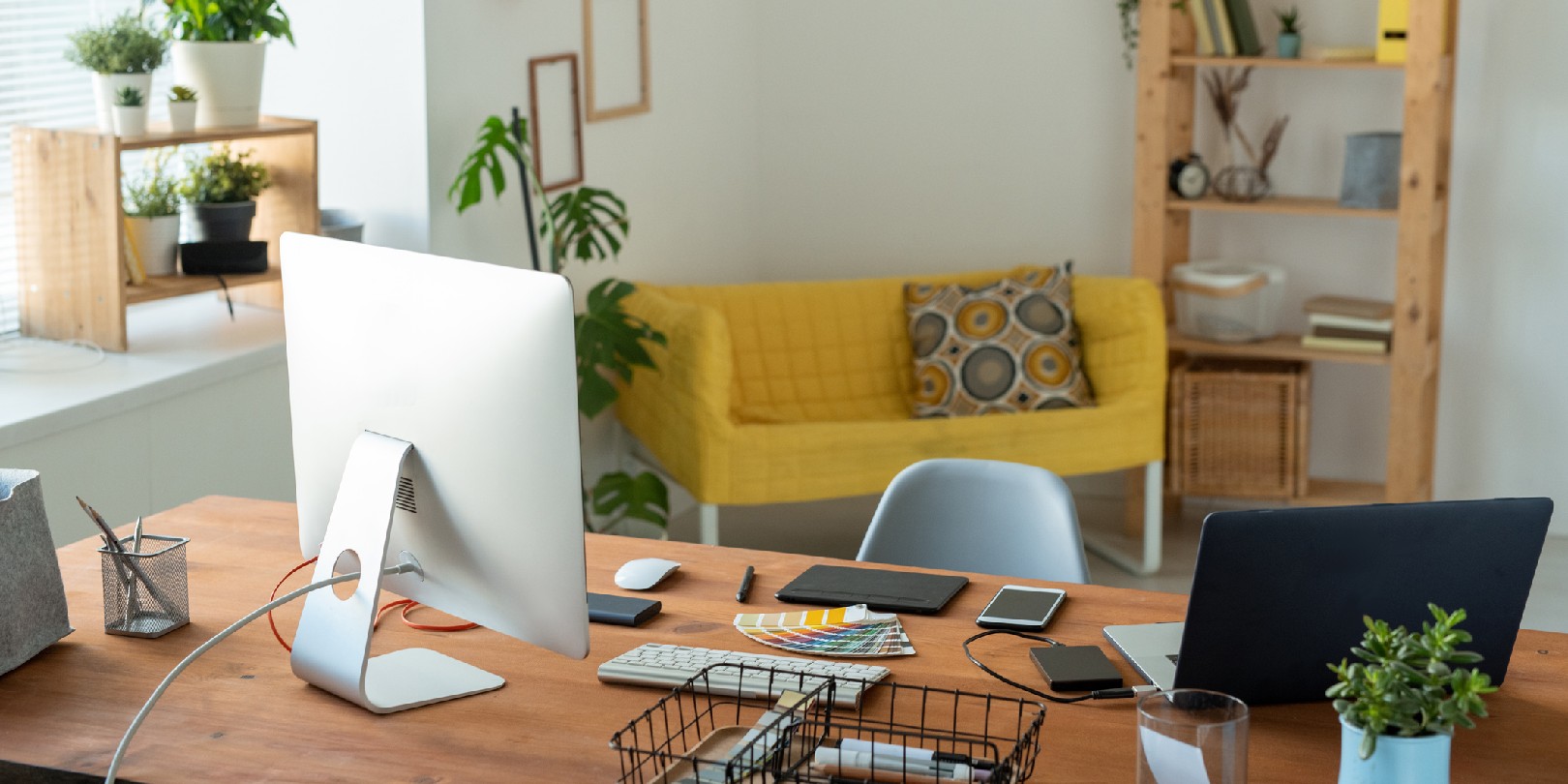 Workplace of contemporary manager or freelancer with computer monitor standing on wooden table surrounded by home environment