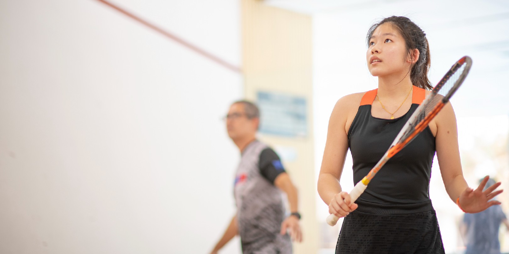 Asian squash coach father guiding teaching his daughter squash sport practicing together in squash court