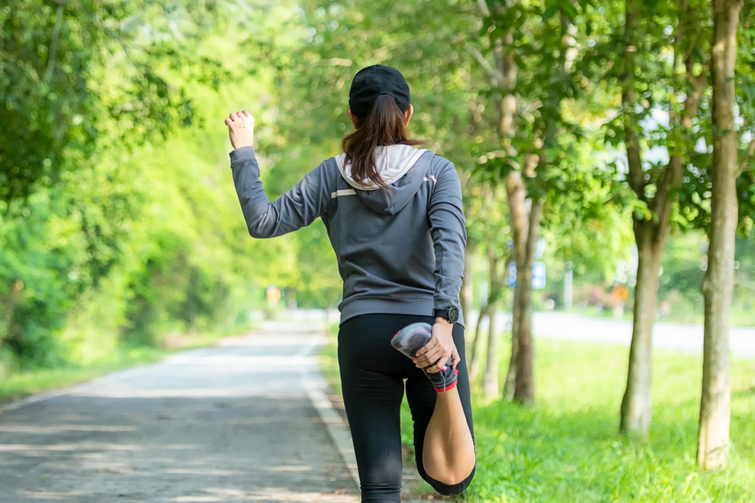 Healthy woman warming up before jogging run and relax stretching her arms and looking away in the road outdoor